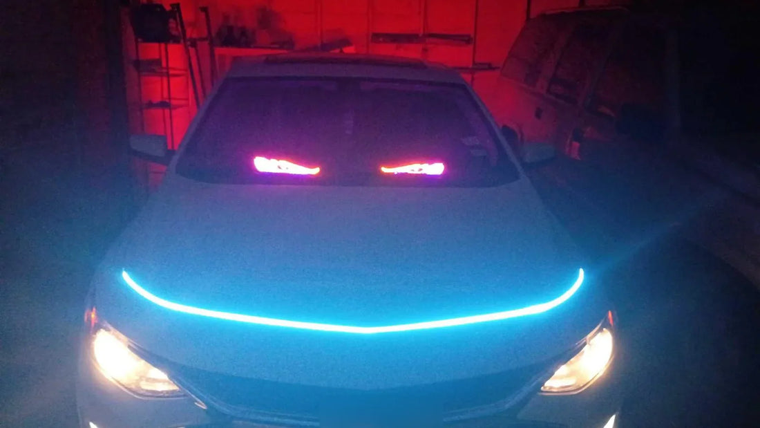 Cyan hood LED strip and red garage lighting on a parked car exterior