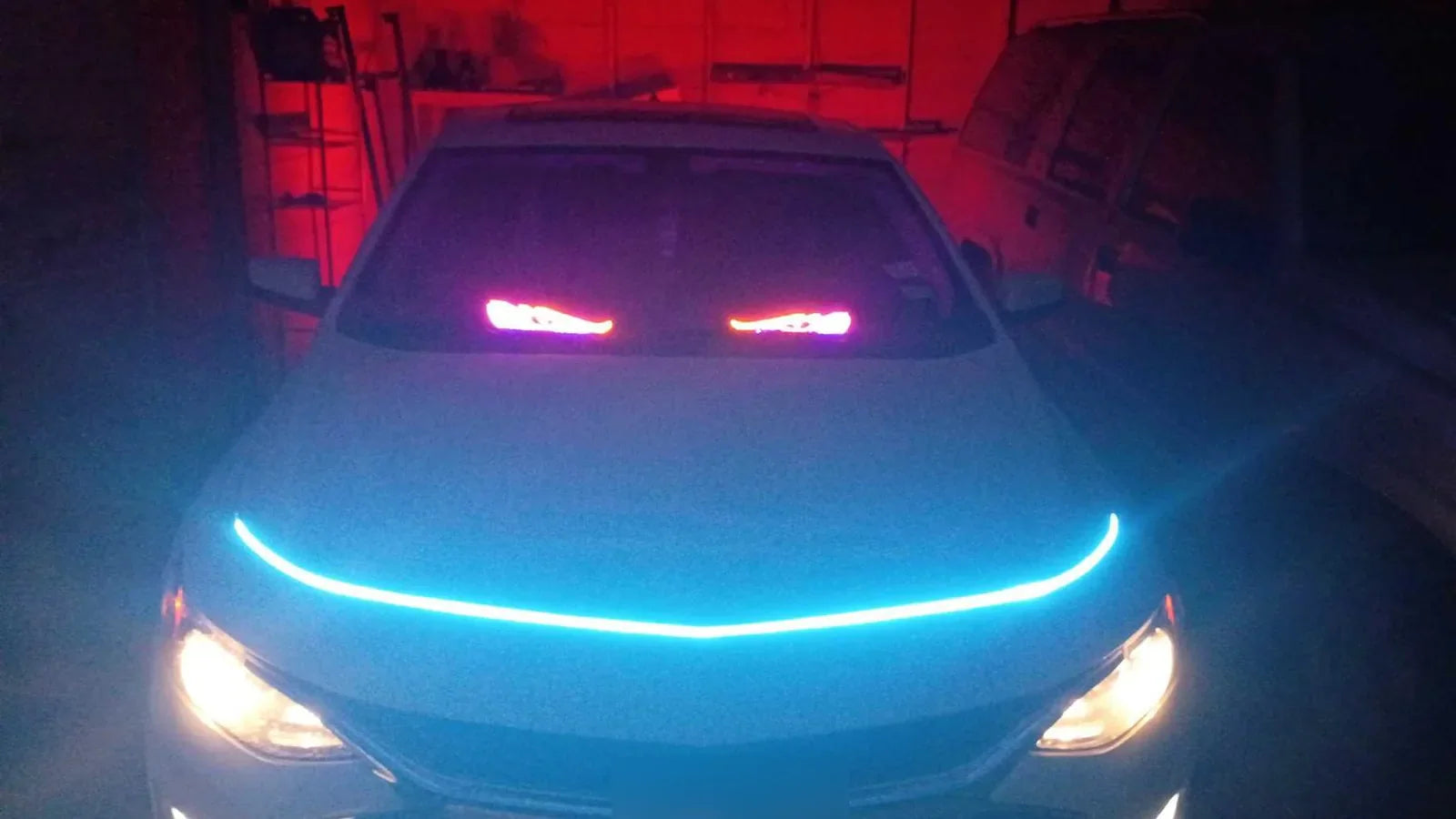 Cyan hood LED strip and red garage lighting on a parked car exterior