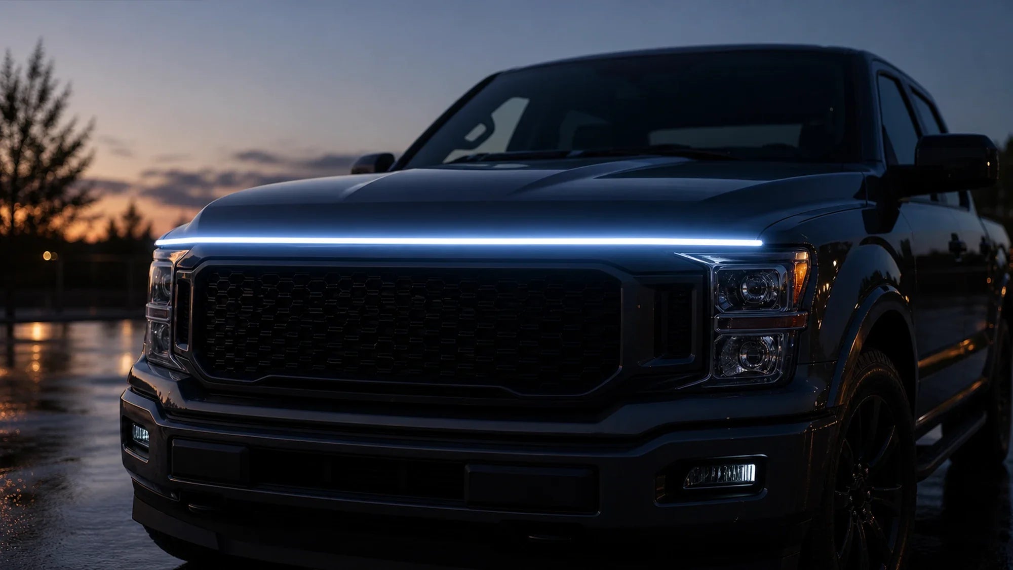 Parked pickup with a thin hood-line LED accent glow across the front grille at dusk