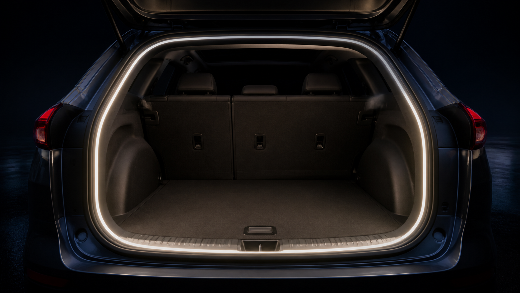 Open SUV cargo area outlined by a continuous white rear trunk light strip at night