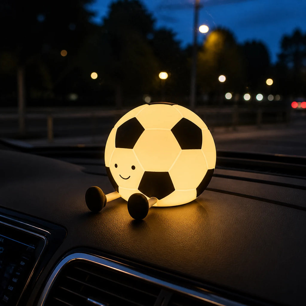 Football silicone night light glowing on a parked car dashboard at night