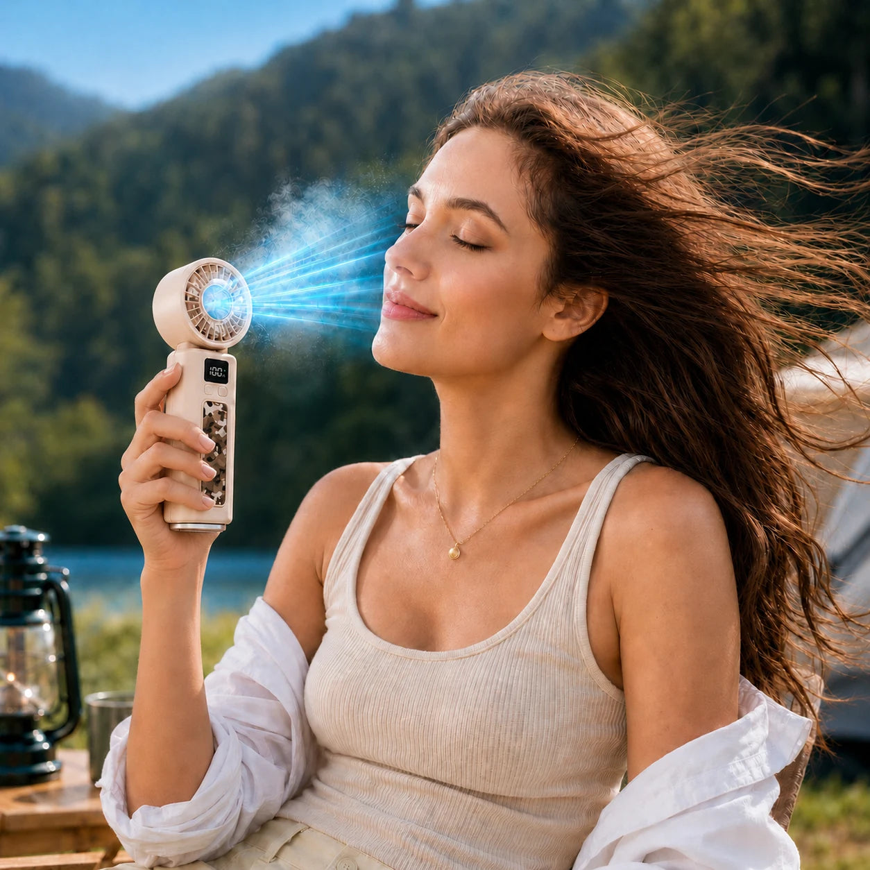 Woman using beige ice energy folding handheld fan outdoors with blue cooling airflow