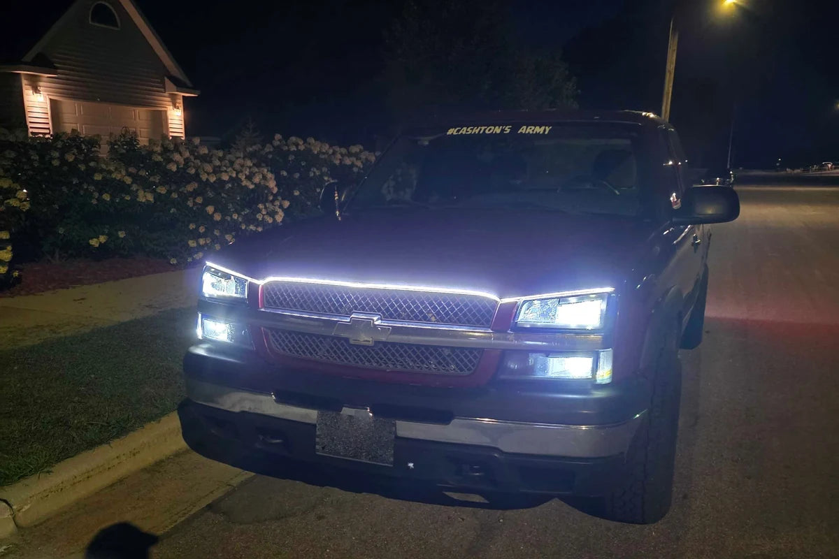 White LED hood accent strip following a pickup grille line in a driveway at night.