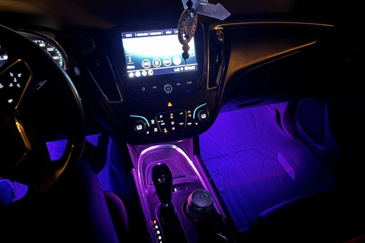Purple RGB footwell lights brightening the lower cabin, center console, and passenger floor area.