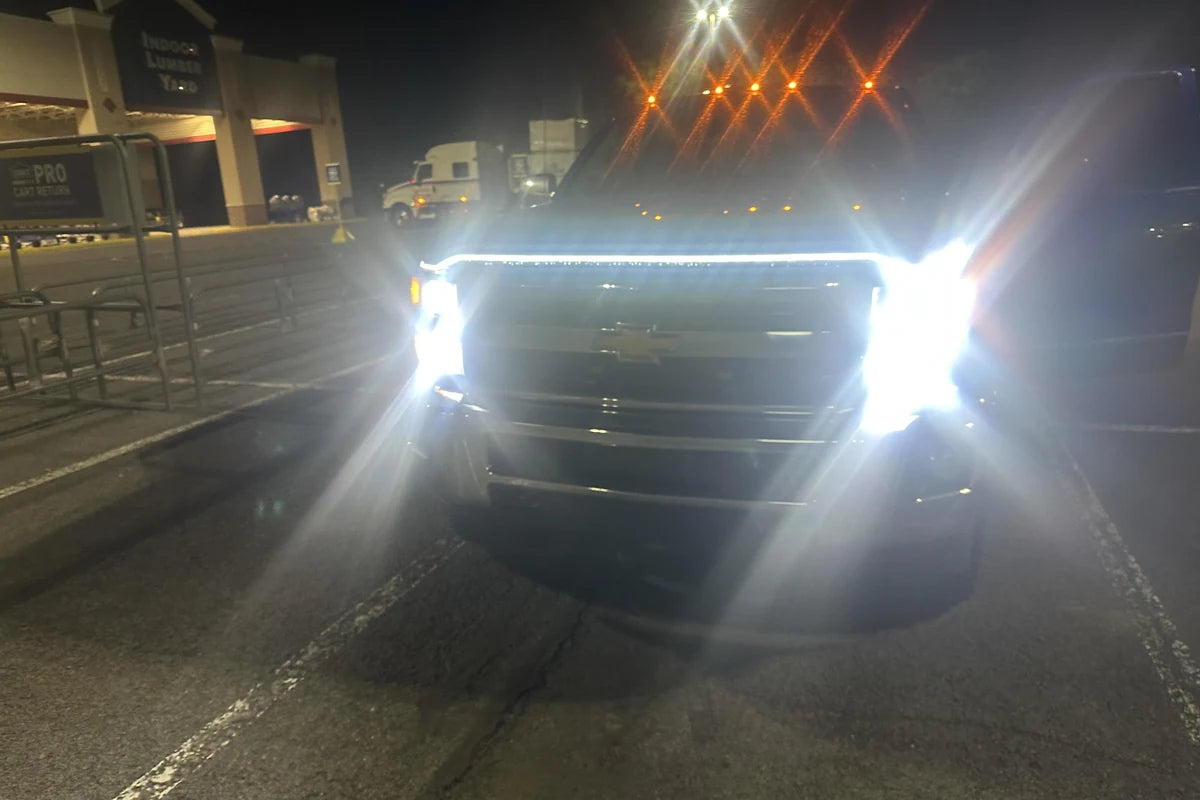 White truck hood LED light strip spanning the front end in a night parking lot.